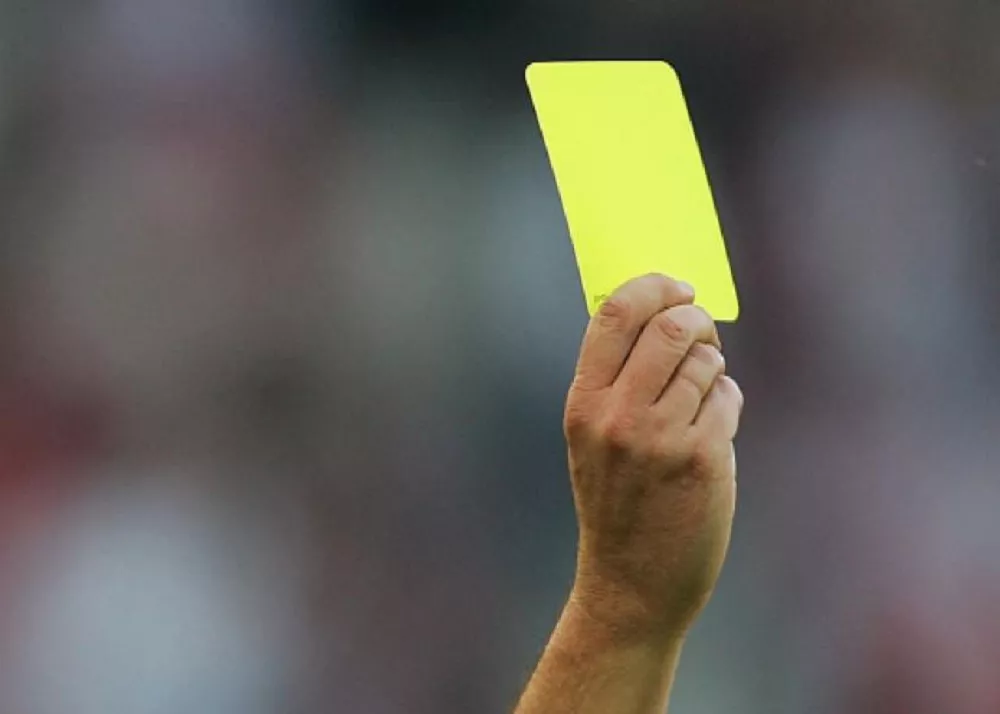 il cartellino giallo sollevato dall'arbitro che ammonisce il giocatore